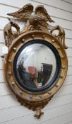 A 19th century gilt and composite circular convex mirror with eagle pediment, width 60cm height