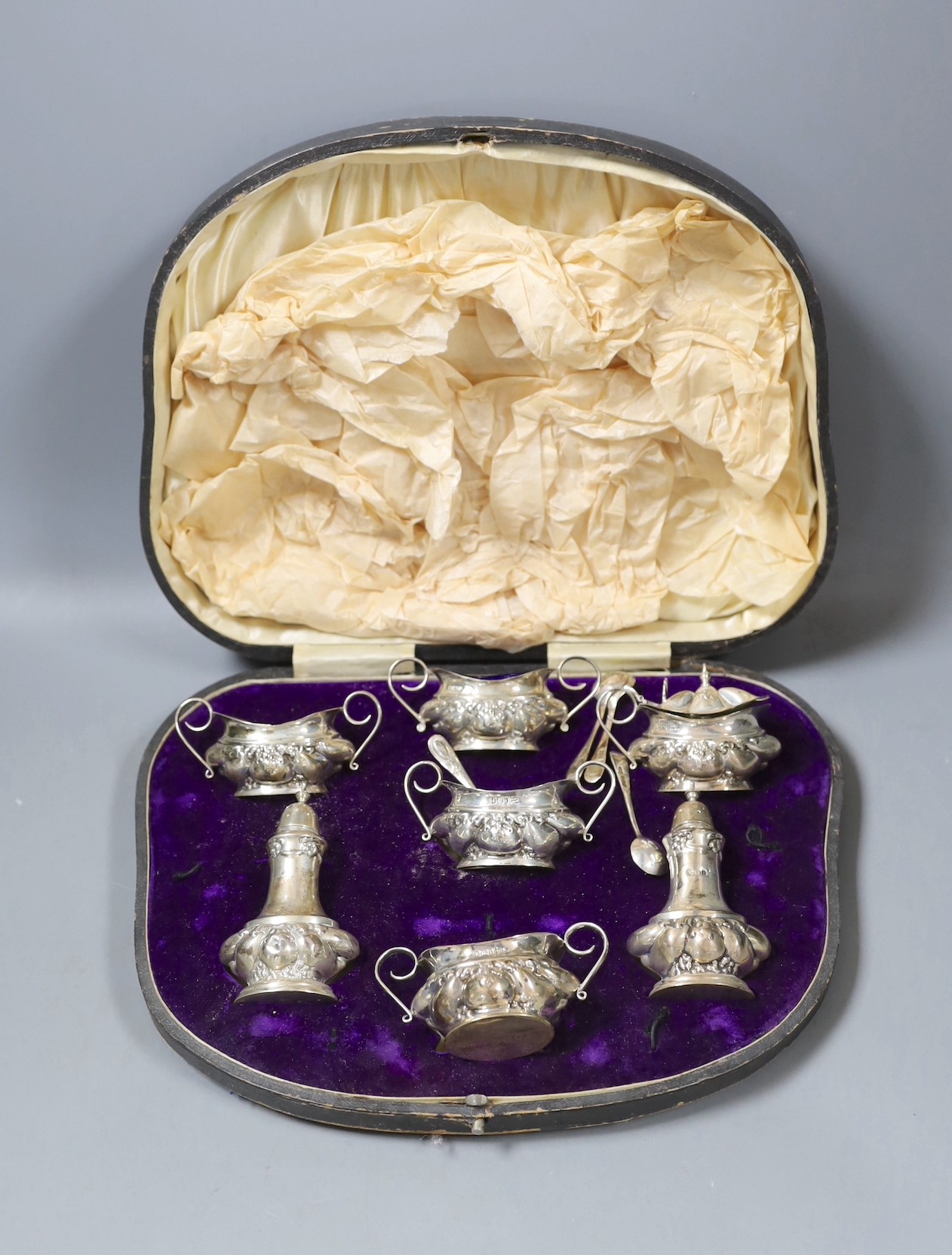 A late Victorian embossed silver six piece condiment set, together with four spoon, Sheffield, 1901,