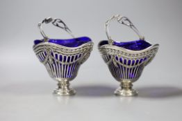 A pair of continental pierced white metal sugar baskets, with shaped blue glass liners, diameter