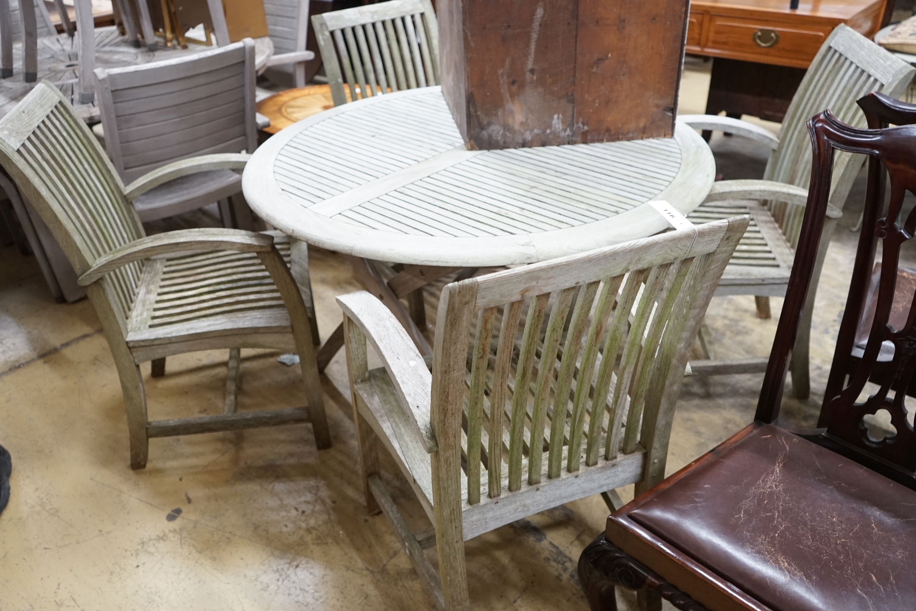 A circular weathered teak folding garden table, diameter 120cm, height 74cm and four teak chairs