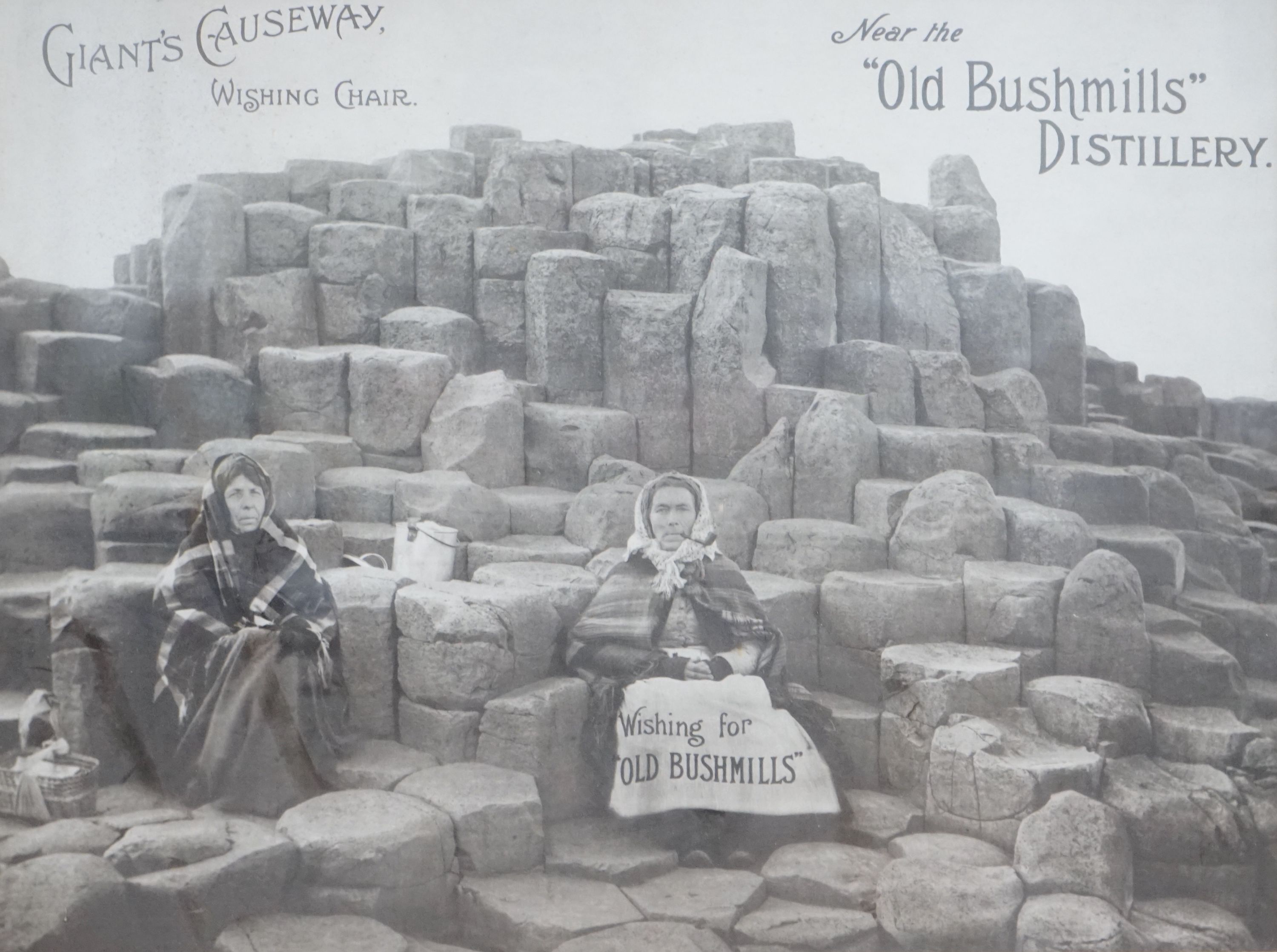 A monochrome advertising print for Old Bushmills Distillery, Giants Causeway, Wishing Chair, 39 x