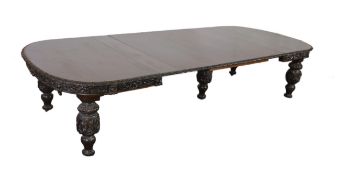 A late Victorian carved oak extending dining table, with rounded D shaped ends and four leaves,