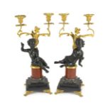 A pair of Louis XVI style bronze and ormolu two light candelabra, each with seated putto stem and