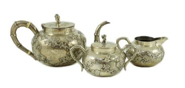 A 19th century Chinese Export silver three piece tea set by Cumshing? decorated with birds amid