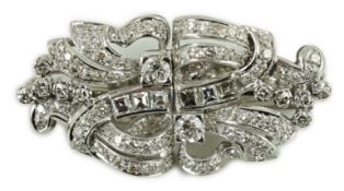 A mid 20th century platinum and diamond cluster double clip brooch, of scrolling form and set with