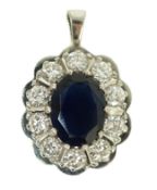 A modern 18ct white gold, sapphire and diamond set oval cluster pendant, the sapphire weighing