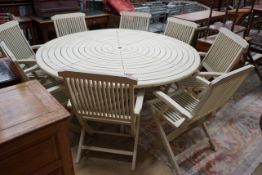 A circular painted teak garden table, diameter 180cm, height 72cm and eight matching folding