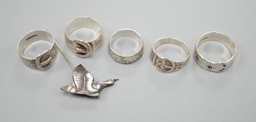 Four assorted silver buckle rings, including one set with red stones, an engraved silver band and