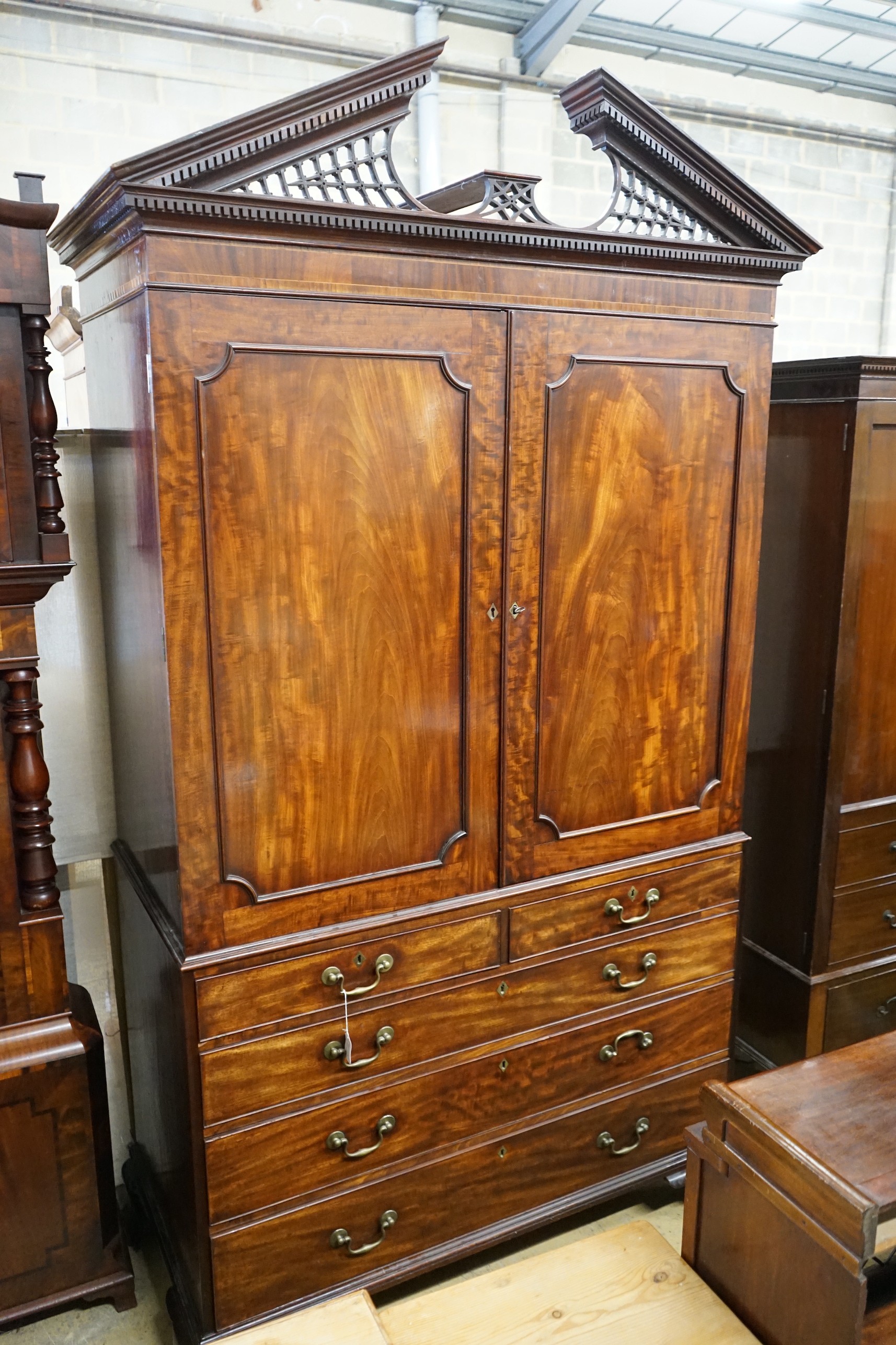 A George III flamed mahogany linen press with broken arch pediment, interior adapted, width 64cm,