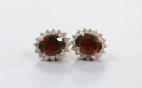 A modern pair of yellow metal, garnet and diamond cluster set oval earrings, 11mm, gross weight 4.