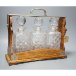 Early 20th century Betjemann's patent oak 3 bottle tantalus,32 cms high.