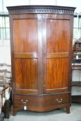 An early 20th century George III style mahogany bowfront wardrobe, with hanging space and one long