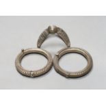 Two 20th century Indian white metal hinged bracelets and a similar shaped bangle.