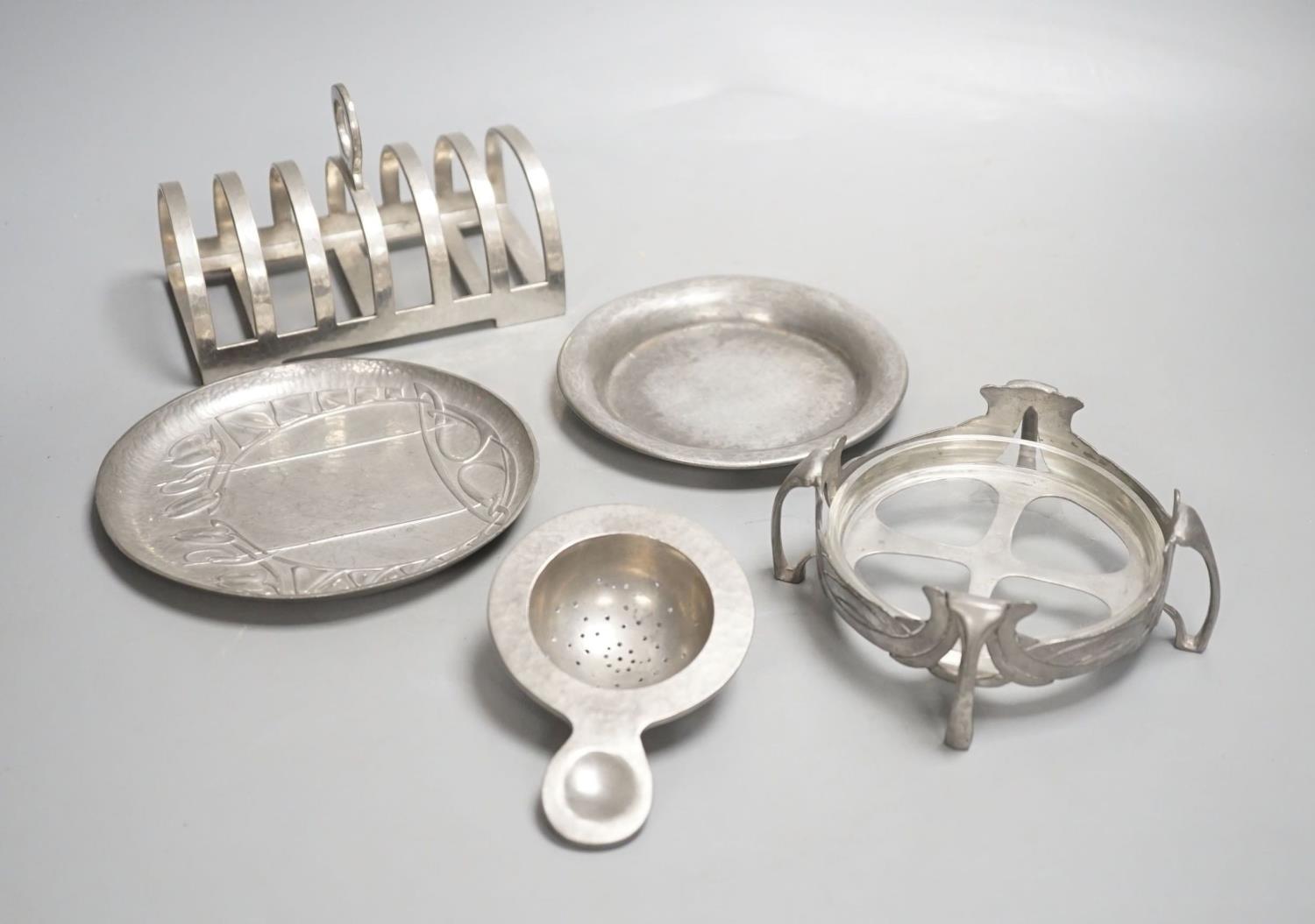 A Tudric seven bar toastrack, three Tudric serving dishes and a Tudric tea strainer, toast rack