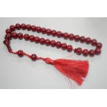 A single strand cherry amber bakelite necklace, 92cm including tassel, gross weight 88 grams.