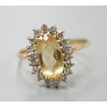 A modern yellow metal, yellow topaz and diamond set oval cluster ring, size T, gross weight 3.7