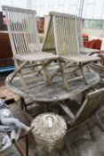 A weathered teak oval garden table, length 178cm, width 120cm, height 77cm and eight folding chairs,