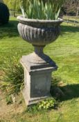 A pair of reconstituted stone campana shaped garden urns on square plinths, diameter 58cm height