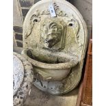 A reconstituted stone garden wall mounted water fountain, with lion mask spout, width 48cm height