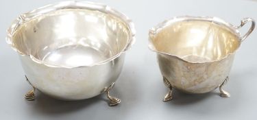 An Edwardian silver sugar bowl and matching cream jug, with cut rims and pad feet, Birmingham