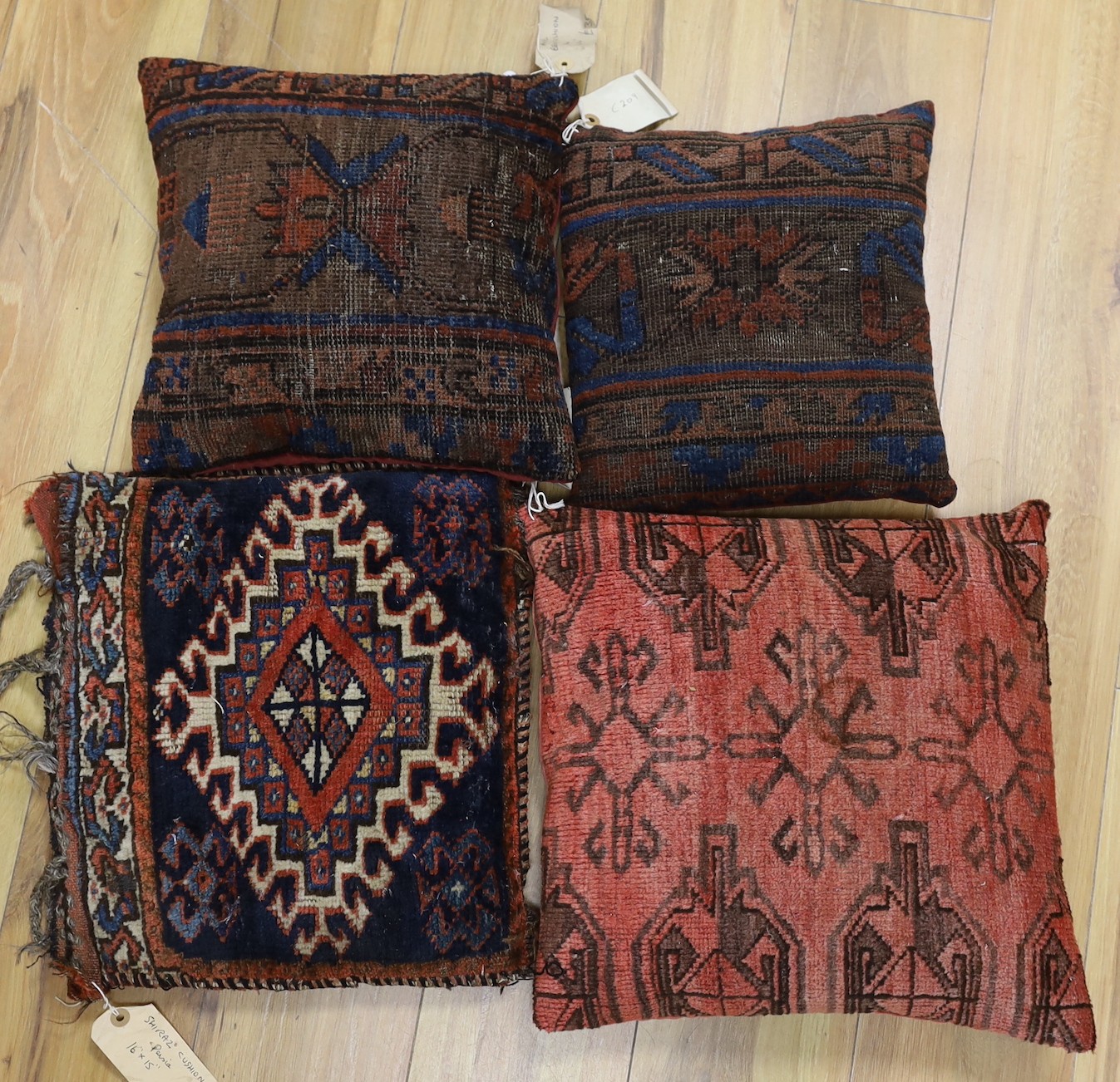 A pair of antique Persian belouch cushions, together with an Afghani Chubbash cushion, 16" x 16" and