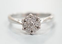 A modern 18ct white gold and seven stone diamond set flower head cluster ring, size O/P, gross