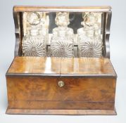 A 19th century mahogany three bottle tantalus, containing baccarat style decanter bottles, width