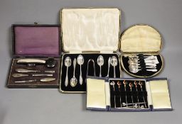A cased set of six white metal and enamel cocktail sticks and three other cased sets including