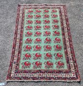 A Kirman Shah rug woven with floral bunches on a green ground within a conforming multi border 184cm