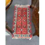 A polychrome flatweave red-field rug, 142 x 72cm