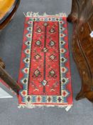 A polychrome flatweave red-field rug, 142 x 72cm