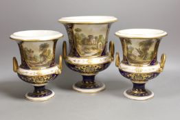 A garniture of three Derby named twin handled cups, View near Belper, Derbyshire, and 'View in North