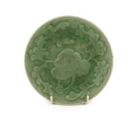 A Chinese celadon glazed small peony dish, Qing dynasty, moulded in relief with a peony flower and