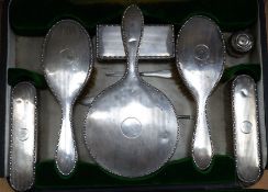A cased George V silver mounted silver eight piece dressing table set, including tray, mirror and