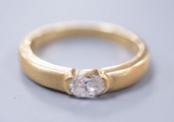 A modern 18ct gold and oval cut solitaire diamond set ring, with sandblasted shank, size K, gross