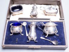 A cased George V silver three piece condiment set, two other silver condiments and a plated