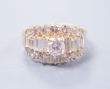 A modern 18ct gold and graduated round and baguette cut diamond set three row cluster ring, size