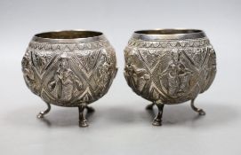 A pair of Indian embossed white metal circular bowls, on three hoof feet, height 82mm.**CONDITION