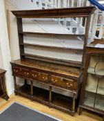 A mid 18th century oak potboard dresser, with an open shelved rack, over four drawers, width