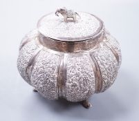 An Indian embossed lobed white metal circular pot and cover, with elephant finial, on three