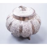 An Indian embossed lobed white metal circular pot and cover, with elephant finial, on three