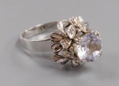 A modern white metal (tests as 18ct) and solitaire white sapphire set flower head ring, in a