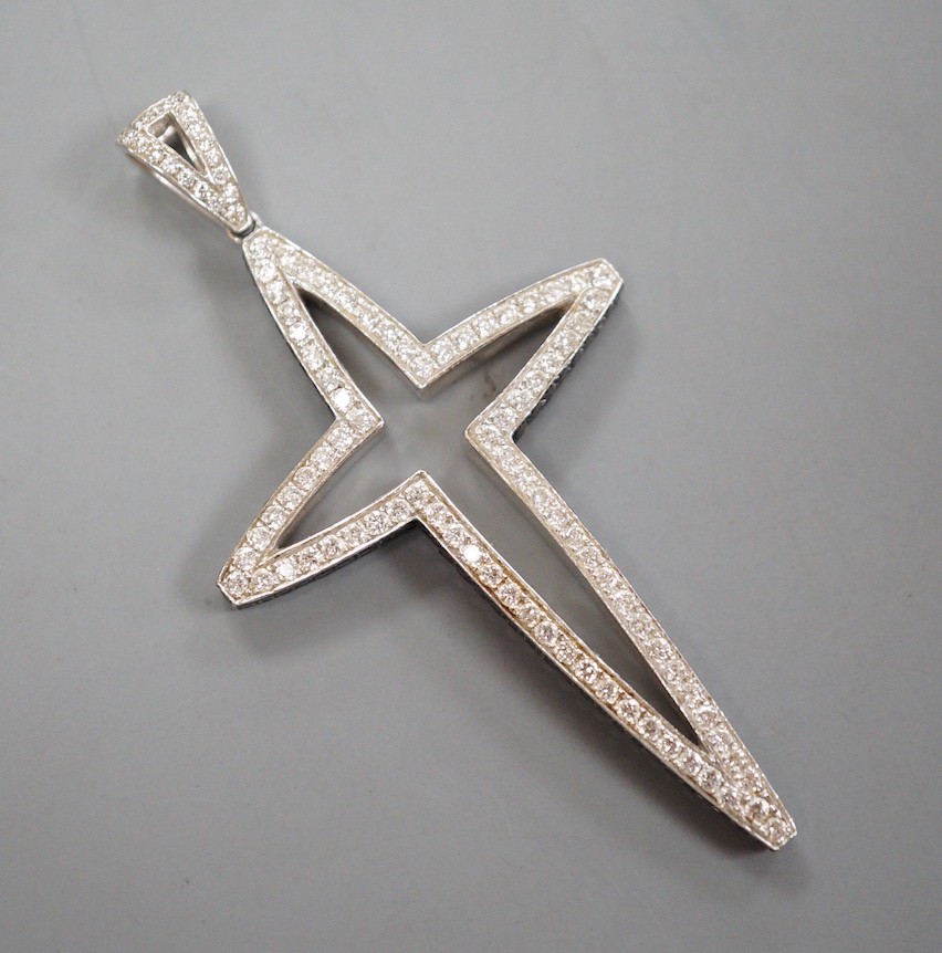 A modern 750 white metal, pave set white and black diamond set stylised cross pendant, overall 59mm,