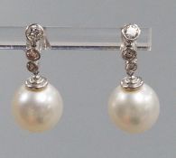 A modern pair of 750 white metal, singe stone South Sea pearl and graduated three stone diamond