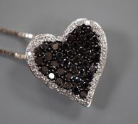 A modern 18ct white gold and pave set white and black diamond set heart shaped pendant, 16mm, on