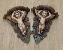 A pair of painted wooden cherubic wall brackets,42cm tall,