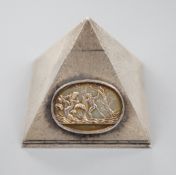 A textured white metal pyramid shaped box, the hinged panel decorated with Greek scene and