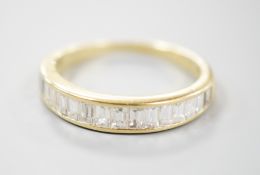 A modern 18ct gold and graduated baguette cut diamond set half eternity ring, size Q, gross 3.4