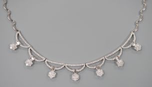 A modern 750 white metal and septuple baguette and round cut diamond cluster set curved link