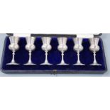 A cased set of six George V silver thistle shaped pedestal tots, E.S. Barnsley & Co, Birmingham,